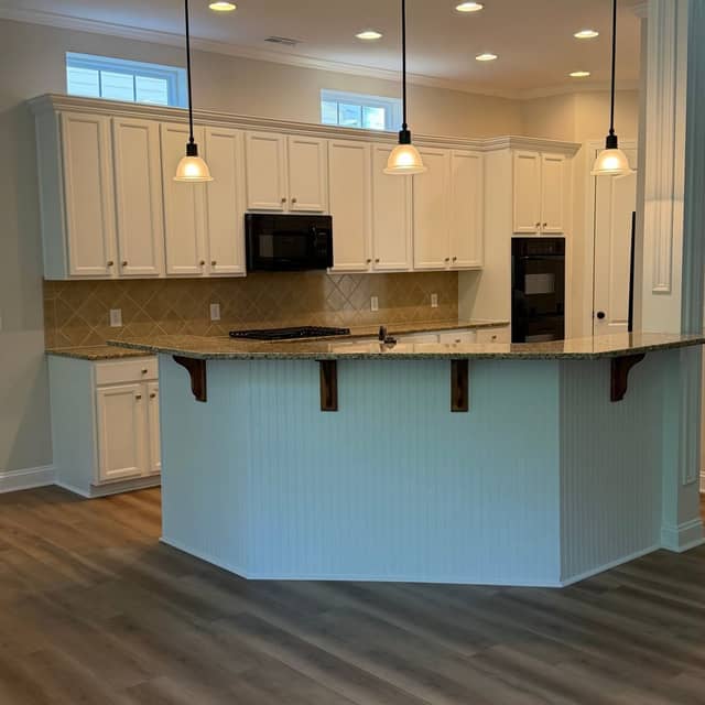 Kitchen with cream painted cabinets, a curved granite breakfast bar and pendant lights