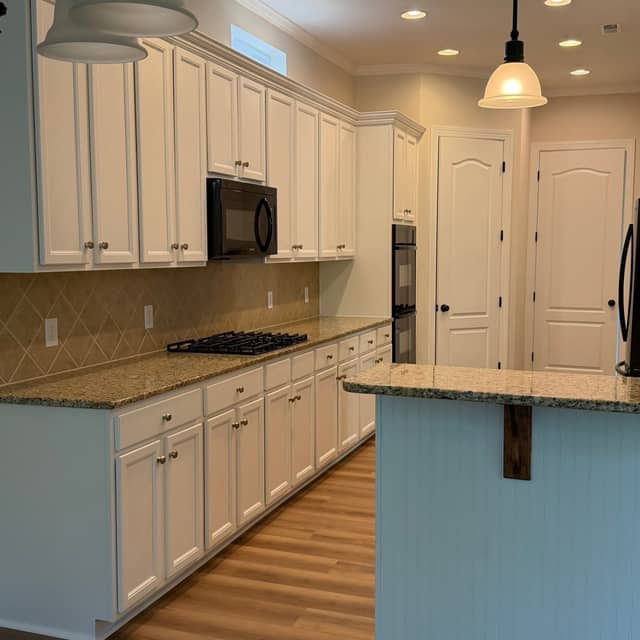 Cream painted kitchen cabinets with granite worktops and a raised breakfast bar