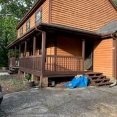 Cedar-sided home stained a warm orange-brown, with the wrap-around porch and steps in a darker brown
