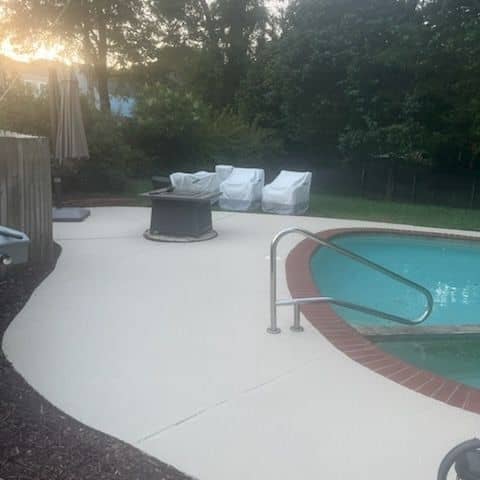 Pool terrace at dusk with spotless concrete decking and a fire pit seating area