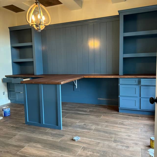 Home office with blue painted built-in shelving and panelling under a coffered ceiling