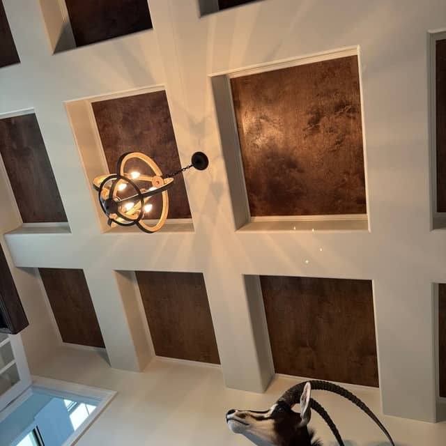 Coffered ceiling with recessed bronze-toned decorative panels and a sputnik pendant light