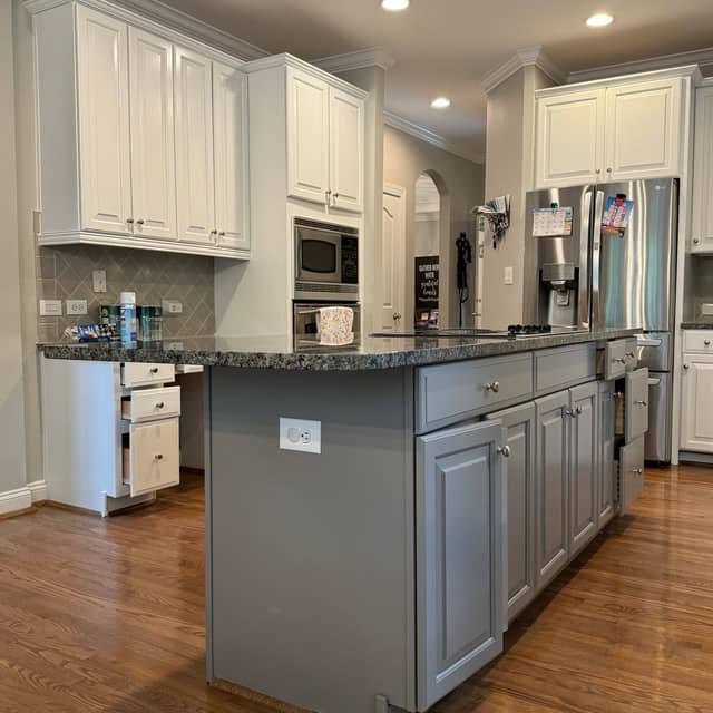 Finished kitchen with white painted wall cabinets, a grey painted island and granite worktops