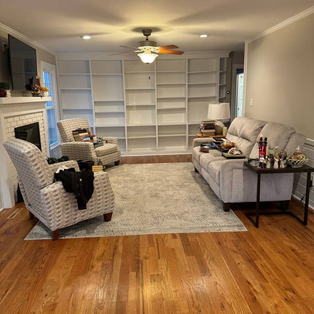 Living room with freshly painted white built-in shelving, grey walls and crown moulding