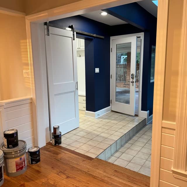 Hallway with navy painted walls, white wainscoting and a white sliding barn door