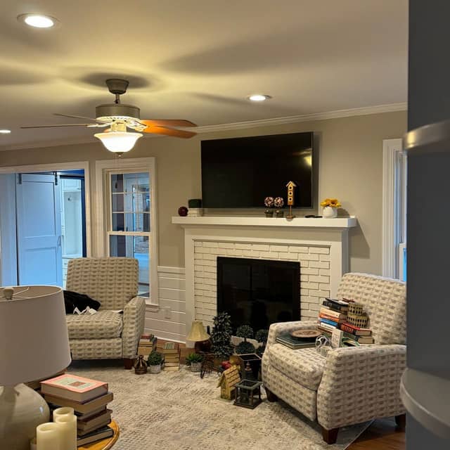 Living room with a painted fireplace surround, soft neutral walls and armchairs either side of the hearth