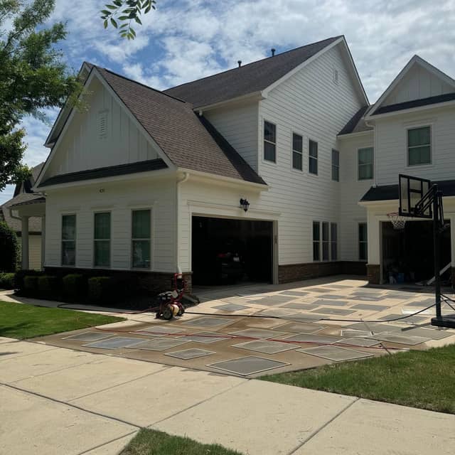 White-painted home with a dark garage door and a stamped concrete driveway