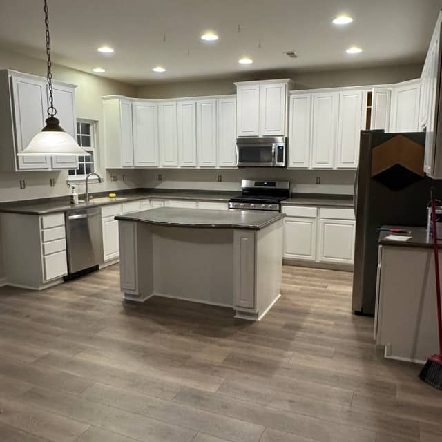 Bright kitchen with white painted cabinets, a large island and pendant lighting